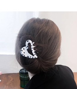 Detail of heart-shaped hair claw clip with black star pattern on white acetate finish