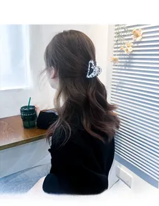 Macro view of heart-shaped acetate claw clip with black and white cow print on model hair