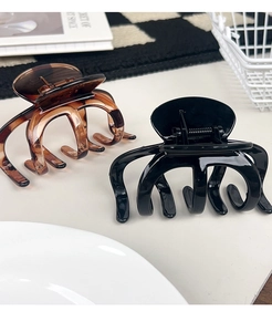 Detail view of large amber and black glossy hair claws on a stylish desktop background