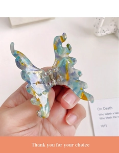 Macro detail of a butterfly-shaped acetic acid hair clip with colorful marble pattern