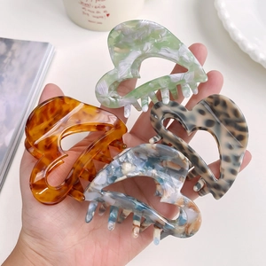 Set of four heart-shaped acetate hair claws in amber, marble, and leopard patterns