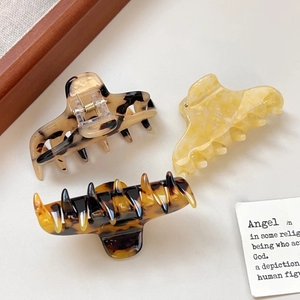 Three acetate hair claws with tortoiseshell and marble patterns in a minimalist layout