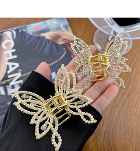 Detailed close-up of butterfly hair claws with pearls and rhinestones on gold metal base