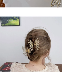 Detailed view of two gold metal butterfly hair claws with rhinestones on a female model