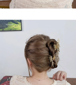 Detailed view of two gold metal butterfly hair claws with pearls and rhinestones