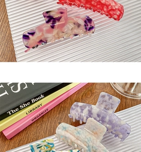 Close-up of large acetate claw clips with floral and marble patterns on a white tray