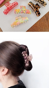 Detail of four acetate shark hair claws in marble, tortoiseshell, and floral patterns