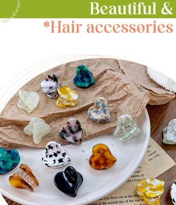 Detailed view of heart-shaped acetate mini hair clips in various marble and amber patterns
