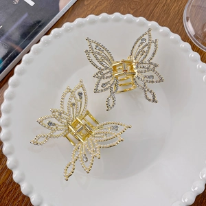 Elegant gold butterfly hair clips with white pearls and rhinestones on a white plate