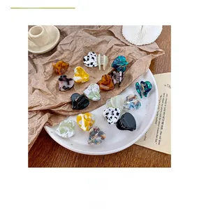 Close-up of heart-shaped acetate hair claw clips with various marble and tortoiseshell patterns