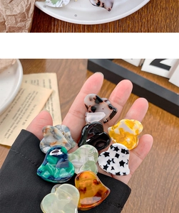 Close-up of heart-shaped mini acetate hair claws in various marble colors and patterns