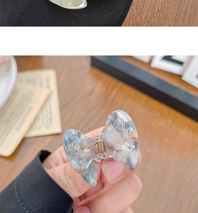 Detail of butterfly hair claw clip with blue marble acetate texture and gold spring