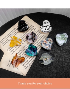Detailed macro view of heart-shaped acetate hair clips in various marble and tortoiseshell patterns