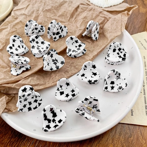 Mini heart-shaped acetate hair clips with black star pattern on white background