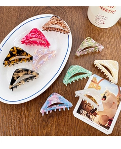 Detail view of assorted hollow triangle acetate hair claws on a ceramic plate