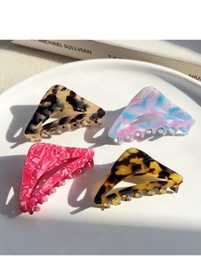 Detail of four triangular acetate hair claws in various marble and tortoiseshell patterns