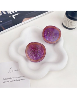 Détail d'une pince à cheveux marbre violet avec bord doré et strass sur plateau