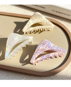 Three triangular acetate hair claws in marble patterns showing texture and hold detail
