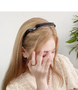 Close-up of a wavy black resin headband styled on a model for a stylish look