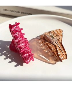 Detailed view of pink marble and tortoiseshell acetate hair claws on a white tray