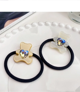 Close-up of bear-shaped hair ties with aurora heart crystals on white tray