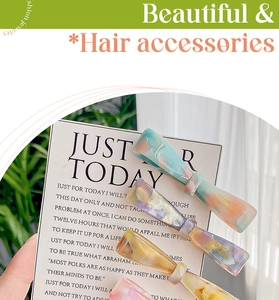 Close-up of handmade acetate marble hair clips with gold lettering on display card