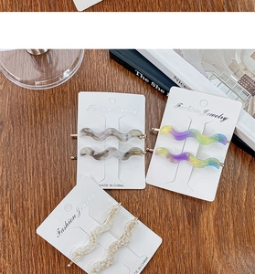 Detailed view of wave-shaped acetate hair clips in grey, purple, and cream textures