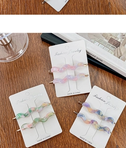 Detailed macro view of acetate wavy hair clips set on display card over wooden texture
