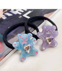 Macro d'élastiques à cheveux ours en acétate avec strass en cœur sur fond de magazine