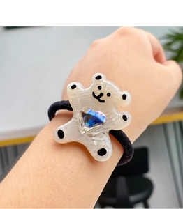 Détail d'un élastique à cheveux ours mignon avec cœur en cristal bleu au poignet