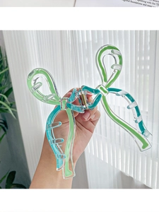 Détail d'une grande pince à cheveux nœud en acrylique avec liserés vert et bleu