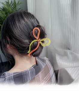 Détail de la pince à cheveux noeud transparent avec motifs orange et jaune sur chignon