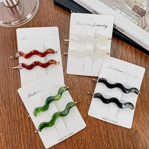 Elegant wavy acetate hair clips set in brown, white, green and black with gold accents