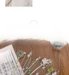 Détail du pic à cheveux Magnolia avec pompon doré et fleur en émail blanc délicat
