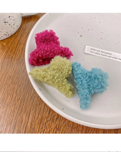 Détail de pinces à cheveux en peluche colorées rose, vert et bleu sur assiette céramique
