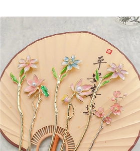 Detail of five vintage metal hairpins with lotus and pearl on a traditional folding fan