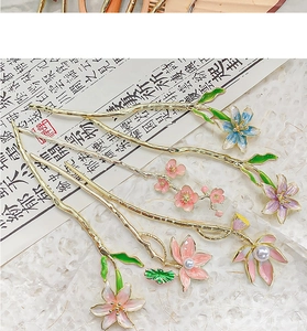 Detailed close-up of golden metal lotus hair pins with colorful enamel and white pearls