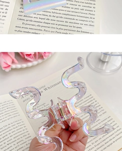 Close-up of iridescent pearlescent shark hair claw clip with wave design and metal spring