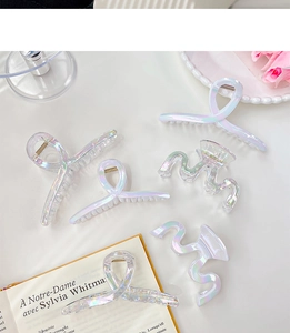 Close-up of holographic mermaid hair clips with pearlescent finish on a white table