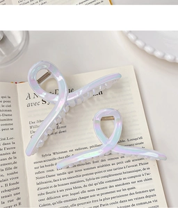 Detail of pearlescent iridescent shark hair clips in large and small sizes on book