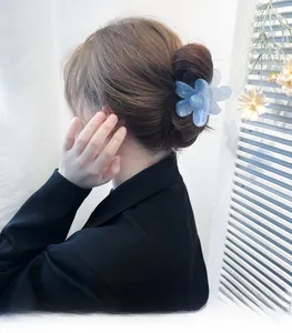 Blue translucent flower hair claw clip with pearlescent finish on a model hair bun