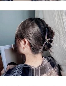 Iridescent mermaid claw clip securing a hair bun in a back view on a model