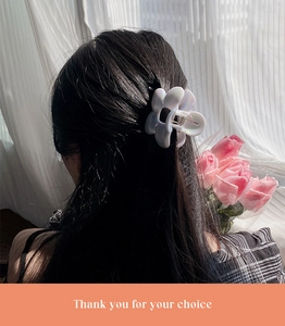 Detailed back view of a large pearlescent flower hair claw clip on wavy hair