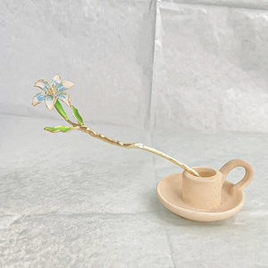 Elegant gold lily hair stick with blue petals and green leaves in a ceramic vase
