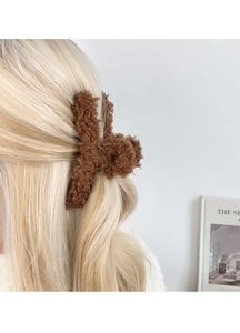 Gros plan détaillé d'une pince à cheveux en peluche marron sur des cheveux blonds
