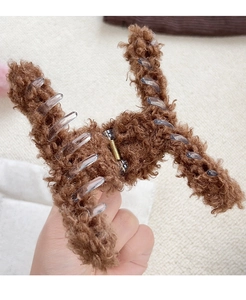 Gros plan détaillé d'une pince à cheveux en fausse fourrure marron avec ressort doré
