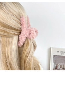 Vue détaillée d'une pince à cheveux en peluche rose stylisée sur des cheveux blonds