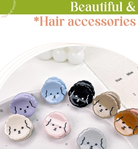 Close-up of mini cartoon dog hair claws in multiple colors on a decorative white tray