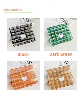 Detail of four plaid hair claws with heart accents in black, green, orange, and cream