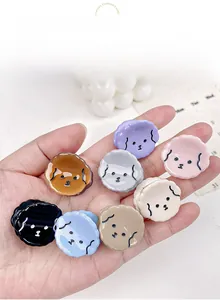 Miniature puppy-shaped hair claws in eight assorted colors held in hand for scale